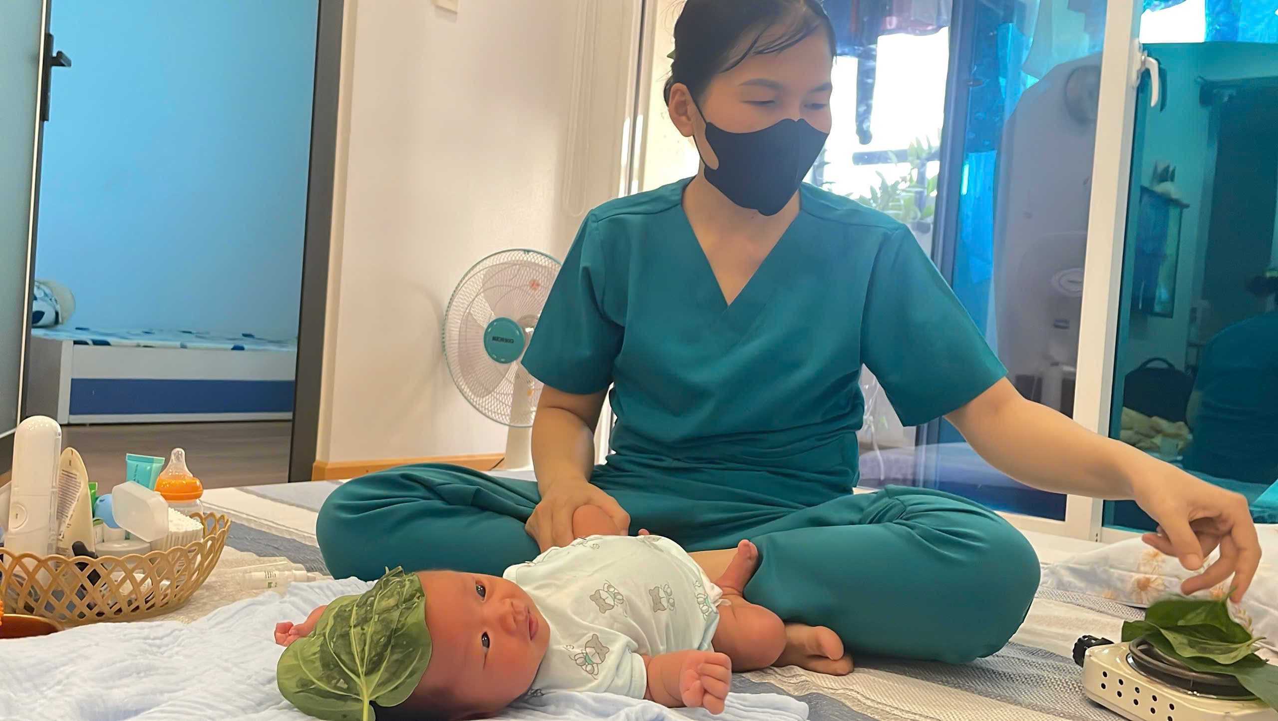 Chuyên viên Be Care đắp lá trầu lên trán bé sơ sinh để giữ ấm