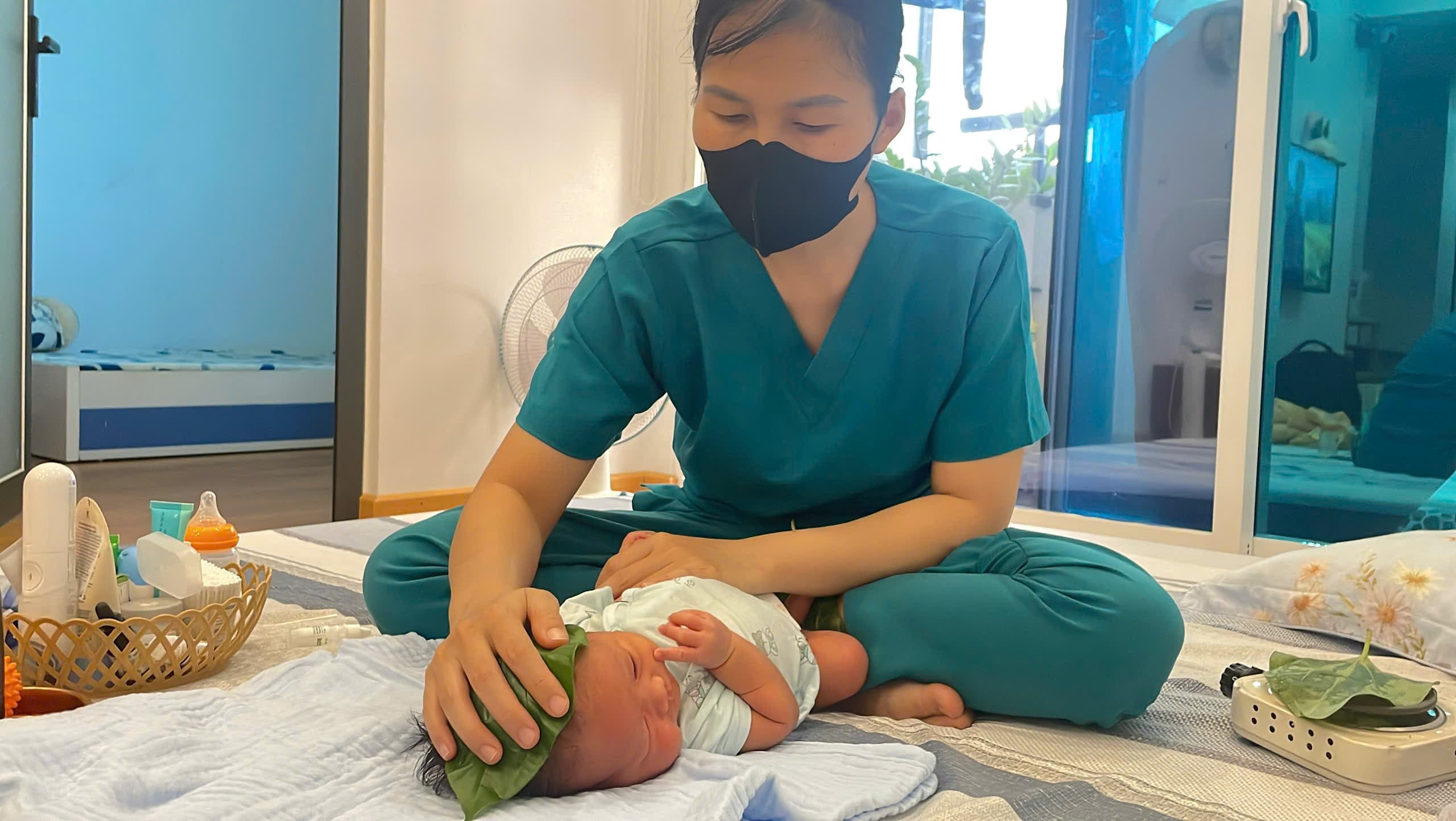 Chuyên viên Be Care nhẹ nhàng đắp lá trầu vùng bụng bé sơ sinh