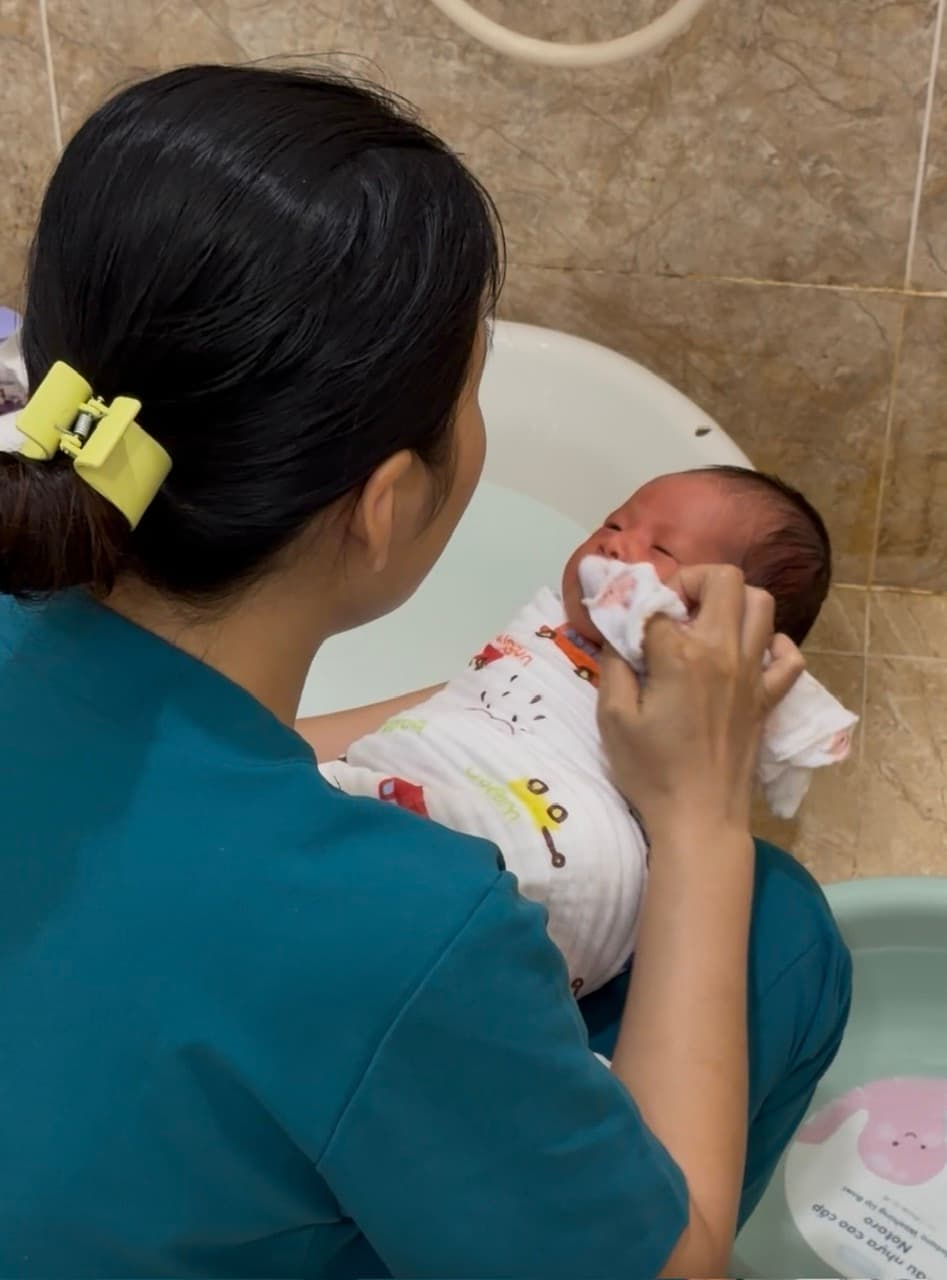 Chuyên viên Be Care tắm bé sơ sinh — lau mặt nhẹ nhàng